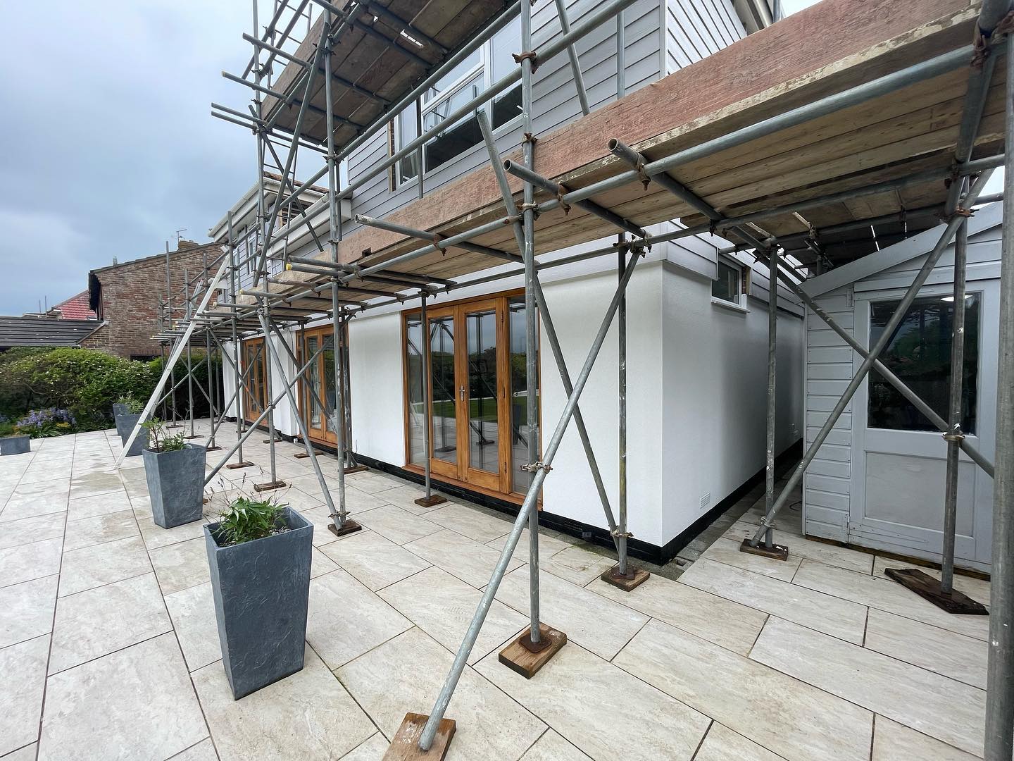 Exterior of a house with scaffolding for renovation work and external wall insulation.