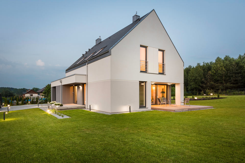 A contemporary house with sleek architecture and beautifully designed landscaping, captured at dusk.